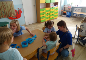 dzieci z rodzicami składają motylki origami