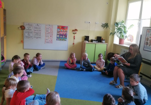 Dzieci siedzą na dywanie.