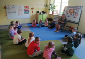 Dzieci siedzą w kręgu na dywanie.