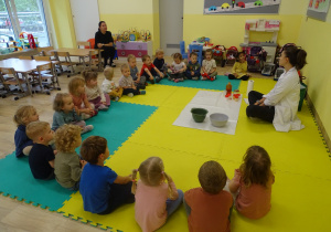 Dzieci siedzą w kole na macie.