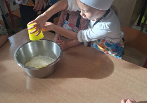 dziewczynka wsypuje mąkę do miski