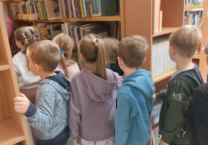 Dzieci chodzą między regałami w bibliotece