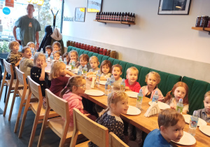Dzieci siedzą przy stole w pizzerii