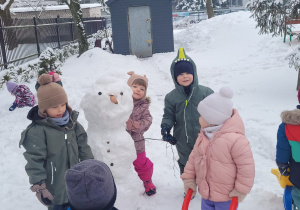 dzieci stoją przy bałwanku