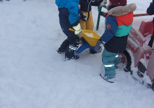 dzieci wiozą śnieg w taczkach
