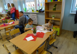 chłopcy siedzą i jedzą ciasto