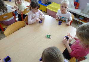 dzieci siedzą przy stole i wysiewają szczypiorek
