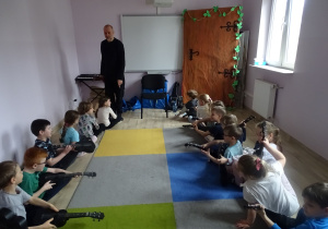 dzieci siedzą i grają na ukulele