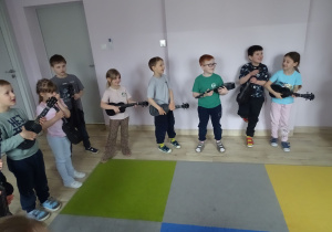 dzieci stoją i grają na ukulele