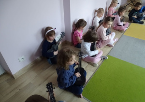 dzieci siedzą i grają na ukulele