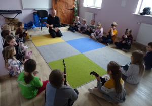 dzieci siedzą i grają na ukulele