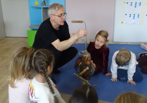 dzieci siedzą i patrzą na marionetkę