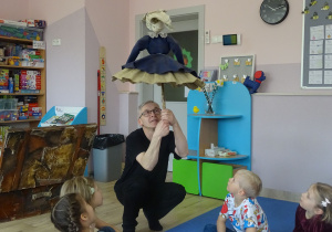 Pan Paweł pokazuje z dziećmi jak poruszać kukłą