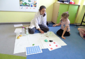 dziewczynka patrzy na przedmiot w misce z wodą
