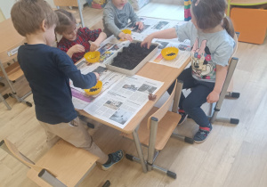 dzieci napełniają doniczki ziemią