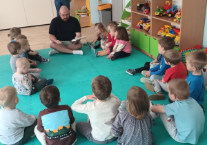 Dzieci siedzą na dywanie w kręgu