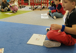 dzieci liczą i ukłądają grzybki na kartkach