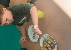 chłopiec nakłada na talerzyk sałatkę