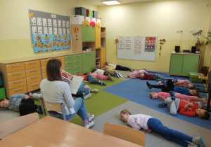 Grupa dzieci słucha ksiązki czytanej przez panią.