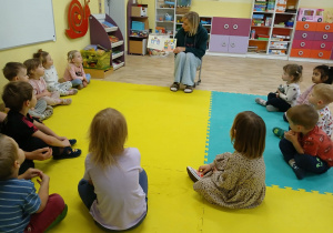 Dzieci słuchają bajki czytanej przez nauczycielkę.