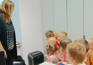 Dzieci oglądają niszczarkę do dokumentów.