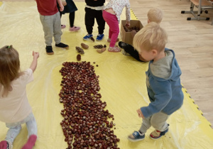 Dzieci układają drzewo z kasztanów.