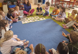 Dzieci siedzą w kole na dywanie.