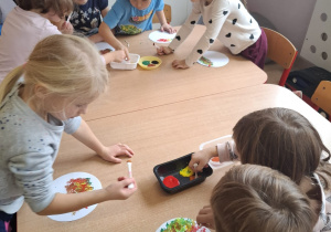 Dzieci malują drzewa.