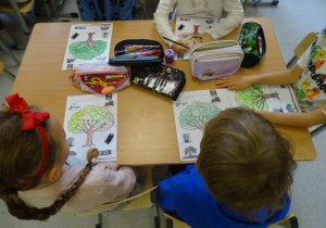 Dzieci kolorują drzewo.