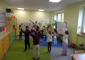 Dzieci ćwiczą na dywanie.