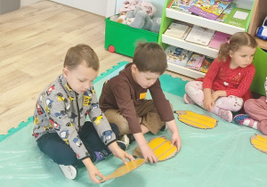 dzieci doklejają taśmę do szablonu jeża