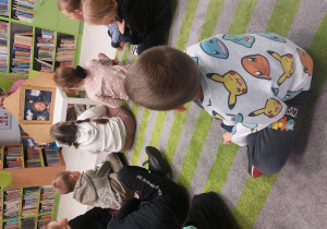 Dzieci siedzą na dywanie i oglądają teatrzyk