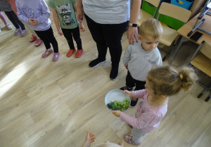 Dzieci podają sobie talerz z owocem