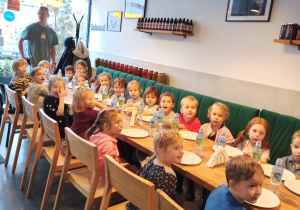 Dzieci siedzą przy stole w pizzerii