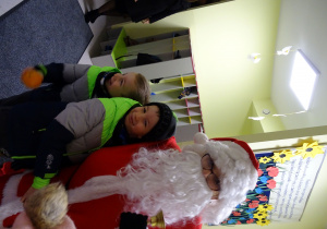 Święty Mikołaj i jego pomocnicy witają dzieci, które przyszły do przedszkola.