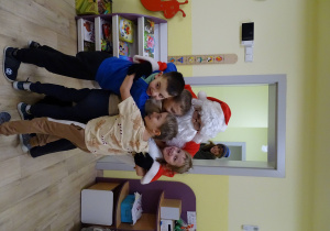 Święty Mikołaj i jego pomocnicy witają dzieci, które przyszły do przedszkola.