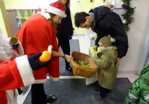 Święty Mikołaj i jego pomocnicy witają dzieci, które przyszły do przedszkola.