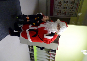 Święty Mikołaj i jego pomocnicy witają dzieci, które przyszły do przedszkola.