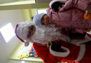 Święty Mikołaj i jego pomocnicy witają dzieci, które przyszły do przedszkola.