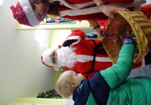 Święty Mikołaj i jego pomocnicy witają dzieci, które przyszły do przedszkola.