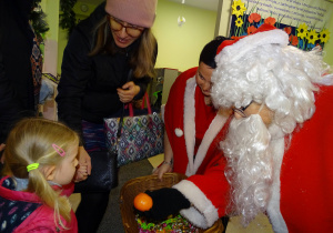 Święty Mikołaj i jego pomocnicy witają dzieci, które przyszły do przedszkola.