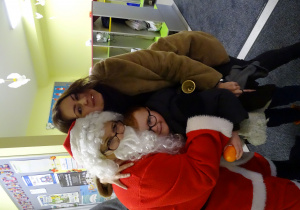 Święty Mikołaj i jego pomocnicy witają dzieci, które przyszły do przedszkola.