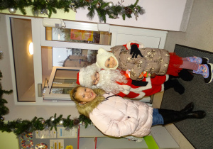 Święty Mikołaj i jego pomocnicy witają dzieci, które przyszły do przedszkola.