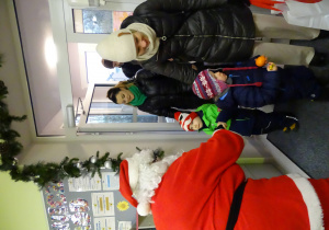 Święty Mikołaj i jego pomocnicy witają dzieci, które przyszły do przedszkola.