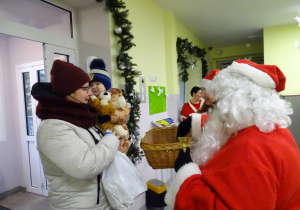 Święty Mikołaj i jego pomocnicy witają dzieci, które przyszły do przedszkola.