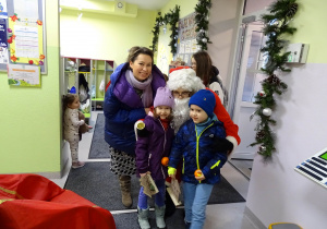 Święty Mikołaj i jego pomocnicy witają dzieci, które przyszły do przedszkola.