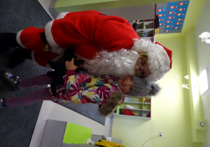 Święty Mikołaj i jego pomocnicy witają dzieci, które przyszły do przedszkola.