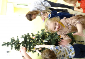 Wieszanie ozdobionych pierników na przedszkolną choinkę.