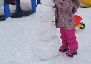 dziewczynka lepi bałwana