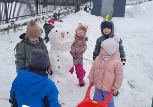 dzieci stoją przy śniegowym bałwanku